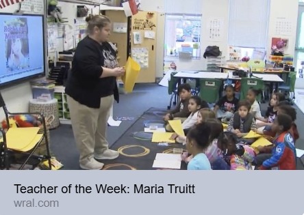  woman standing in front of children sitting on the carpet